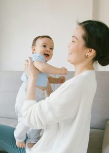 A mother and baby enjoy a happy and loving moment indoors, showcasing their bond.